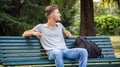 Handsome blond young man sitting on park bench