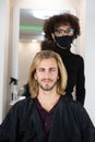 Handsome blonde male client getting haircut by black female hairdresser Royalty Free Stock Photo