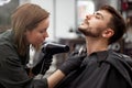 Handsome blue eyed man sitting in barber shop. Hairstylist Hairdresser Woman cutting his hair. Female barber Royalty Free Stock Photo