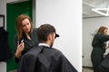 Handsome blue eyed man sitting in barber shop. Hairstylist Hairdresser Woman cutting his hair. Female barber Royalty Free Stock Photo