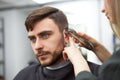 Handsome blue eyed man sitting in barber shop. Hairstylist Hairdresser Woman cutting his hair. Female barber