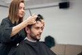 Handsome blue eyed man sitting in barber shop. Hairstylist Hairdresser Woman cutting his hair. Female barber Royalty Free Stock Photo