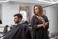 Handsome blue eyed man sitting in barber shop. Hairstylist Hairdresser Woman cutting his hair. Female barber Royalty Free Stock Photo