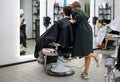 Handsome blue eyed man sitting in barber shop. Hairstylist Hairdresser Woman cutting his hair. Female barber Royalty Free Stock Photo