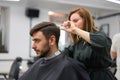 Handsome blue eyed man sitting in barber shop. Hairstylist Hairdresser Woman cutting his hair. Female barber Royalty Free Stock Photo