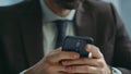 Handsome boss typing sms on smartphone at office close up. Businessman messaging