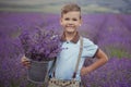 Handsome boy with blond hairs wearing blue tshirt and stylish shorts with pulleys gallows posing on summer field full of lavender