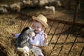 Handsome boy plays with the goatling in hay