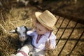 The little boy plays with the goatling in hay
