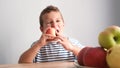 A handsome boy eats a big ripe red apple for breakfast. Healthy food with fruits Royalty Free Stock Photo
