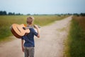 Handsome boy with guitar walking on the road in summer day. Back view Royalty Free Stock Photo