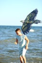 Handsome boy in shorts and a t-shirt teenager launches a kite on the sky on the seashore