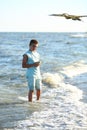 Handsome boy in shorts and a t-shirt teenager launches a kite on the sky on the seashore Royalty Free Stock Photo