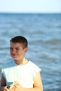 Handsome boy in shorts and a t-shirt teenager launches a kite on the sky on the seashore Royalty Free Stock Photo