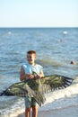 Handsome boy in shorts and a t-shirt teenager launches a kite on the sky on the seashore Royalty Free Stock Photo