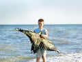 Handsome boy in shorts and a t-shirt teenager launches a kite on the sky on the seashore Royalty Free Stock Photo