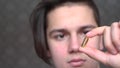 A handsome boy a teenager holds a transparent capsule medicine, pills or vitamins