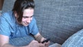 Handsome boy teenager talking on the phone sits on a gray sofa Royalty Free Stock Photo