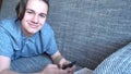 Handsome boy teenager talking on the phone sits on a gray sofa Royalty Free Stock Photo