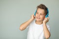 Handsome boy in a white T-shirt listens to music with headphones. The teenager enjoys the music. Isolated on a gray background Royalty Free Stock Photo