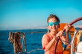 A handsome boy of 9-10 years old at the helm of a yacht