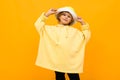 Handsome boy in yellow hoodie smiles and gesticulates isolated on orange background