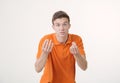 Handsome brown-haired man wearing orange shirt looking angry showing hand gesture and talking something irate over white