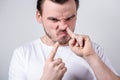 Handsome guy with bristles in a white t-shirt picks his finger in his nose