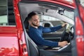 Handsome brunette man sitting in red car with opened door. Royalty Free Stock Photo