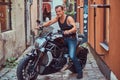 A handsome brutal biker, ride on a motorcycle, in a narrow old Europe street.