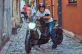 A handsome brutal biker, ride on a motorcycle, in a narrow old Europe street.