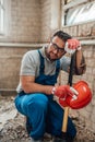 Handsome builder sits on the smashed floor of the construction site