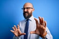 Handsome business bald man with beard wearing elegant tie and glasses over blue background disgusted expression, displeased and