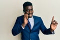 Handsome business black man having conversation talking on the smartphone smiling happy pointing with hand and finger to the side Royalty Free Stock Photo