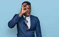 Handsome business black man wearing business suit and tie doing ok gesture shocked with surprised face, eye looking through Royalty Free Stock Photo