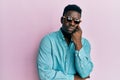 Handsome business black man wearing stylish sunglasses serious face thinking about question with hand on chin, thoughtful about Royalty Free Stock Photo