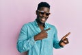 Handsome business black man wearing stylish sunglasses smiling and looking at the camera pointing with two hands and fingers to Royalty Free Stock Photo