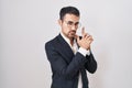 Handsome business hispanic man standing over white background holding symbolic gun with hand gesture, playing killing shooting Royalty Free Stock Photo