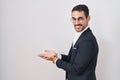 Handsome business hispanic man standing over white background pointing aside with hands open palms showing copy space, presenting Royalty Free Stock Photo