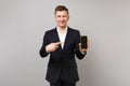 Handsome business man in classic black suit pointing index finger on mobile phone with blank empty screen isolated on Royalty Free Stock Photo