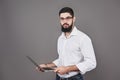 Handsome business man in glasses and suit holding laptop in hands and writing something. Side view. Isolated gray Royalty Free Stock Photo