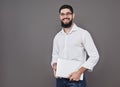 Handsome business man in glasses and suit holding laptop in hands and writing something. Side view. Isolated gray Royalty Free Stock Photo