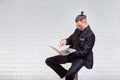 Handsome business man in glasses and suit holding laptop in hands and writing something. Side view. On white brick Royalty Free Stock Photo