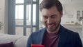 Handsome business man laughing with phone at home. Guy reading funny text.