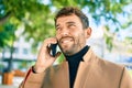 Handsome business man wearing elegant jacket using smartphone smiling happy outdoors Royalty Free Stock Photo