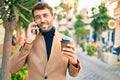 Handsome business man wearing elegant jacket using smartphone smiling happy outdoors Royalty Free Stock Photo