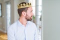 Handsome business man wearing golden crown as a king or prince looking to side, relax profile pose with natural face with