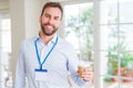 Handsome business man wearing id bagde with a big smile on face while drinking take away coffee in a paper cup Royalty Free Stock Photo