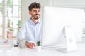 Handsome business young man working using computer, smiling confident and concentrated at the office