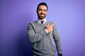 Handsome businessman with beard wearing casual tie standing over purple background cheerful with a smile of face pointing with Royalty Free Stock Photo